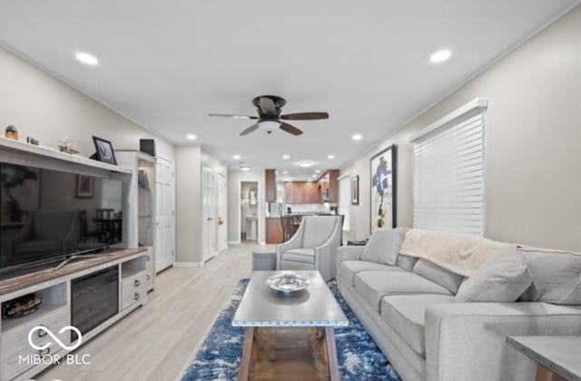 living room with light hardwood / wood-style flooring, ceiling fan, and crown molding