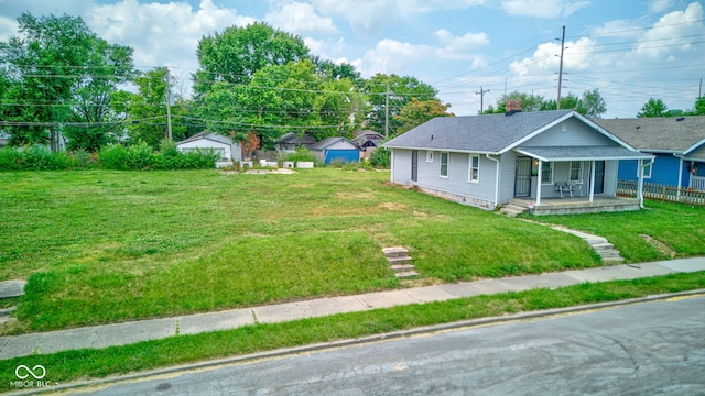 view of front facade with an outbuilding, a porch, and a front yard