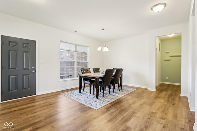 dining room featuring wood-type flooring and an inviting chandelier