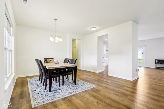 dining room with dark wood-type flooring and a chandelier