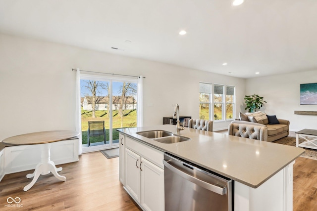 kitchen featuring stainless steel dishwasher, a kitchen island with sink, sink, light hardwood / wood-style floors, and white cabinetry