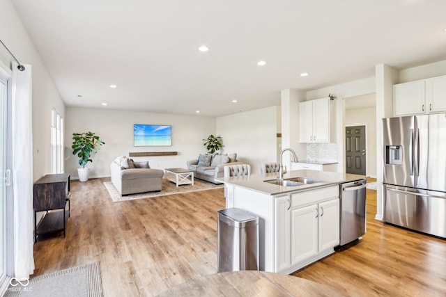 kitchen featuring sink, decorative backsplash, an island with sink, appliances with stainless steel finishes, and white cabinetry