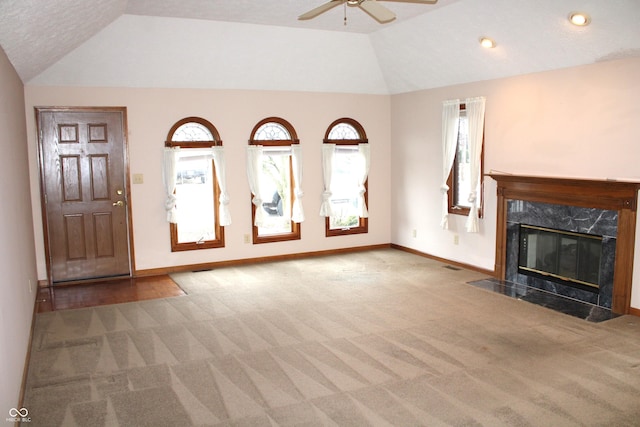 unfurnished living room featuring carpet flooring, a textured ceiling, vaulted ceiling, ceiling fan, and a premium fireplace