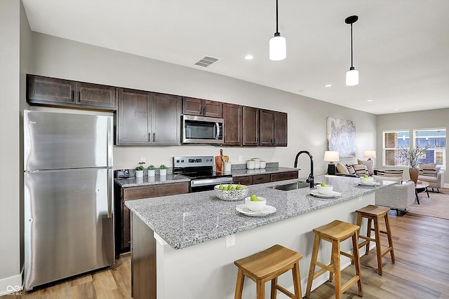 kitchen with dark brown cabinetry, light wood finished floors, visible vents, appliances with stainless steel finishes, and a sink