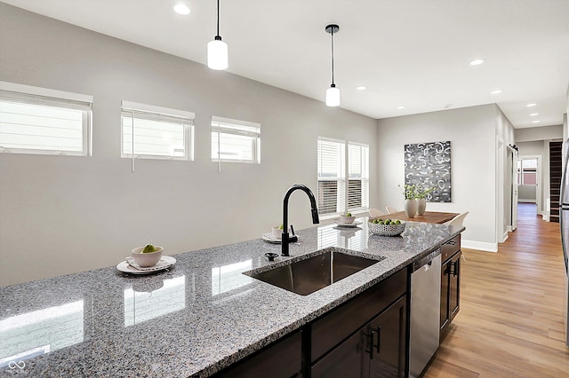 kitchen with stainless steel dishwasher, light wood-style floors, pendant lighting, a sink, and recessed lighting