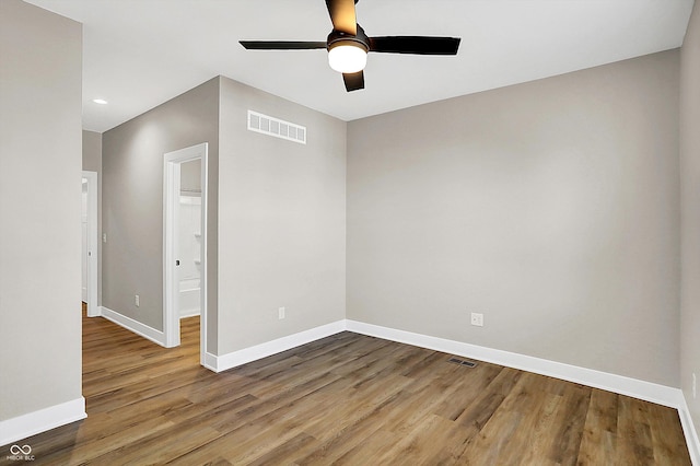 spare room with a ceiling fan, wood finished floors, visible vents, and baseboards