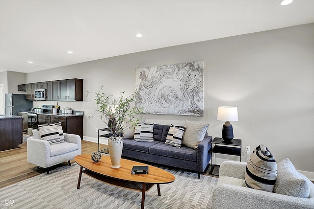 living area featuring baseboards, recessed lighting, and light wood-style floors