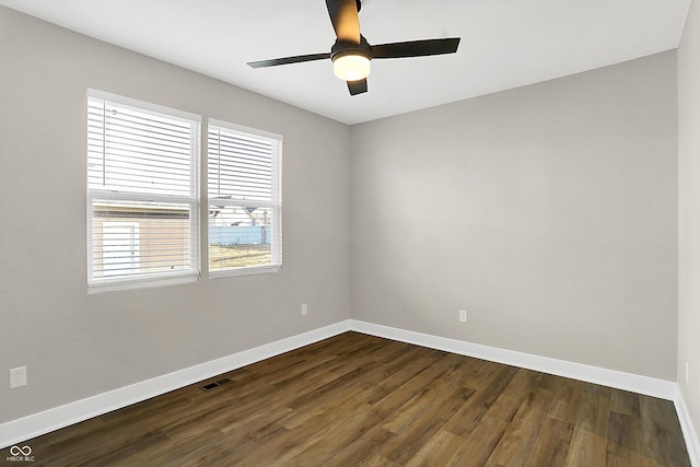 unfurnished room featuring dark wood-style floors, a ceiling fan, visible vents, and baseboards