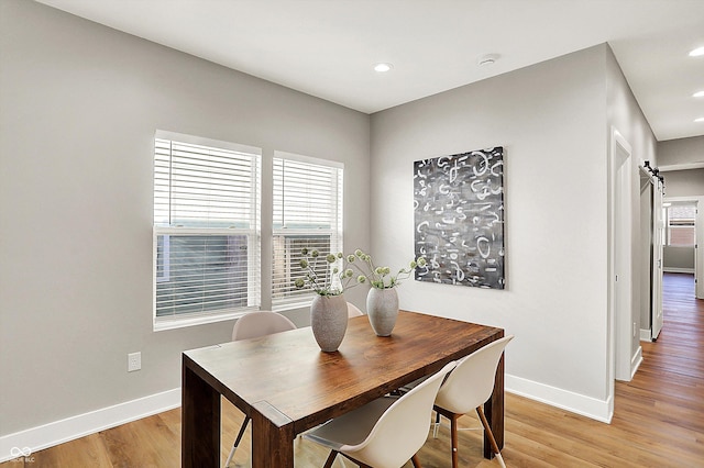 dining space with baseboards, a barn door, recessed lighting, and light wood-style floors