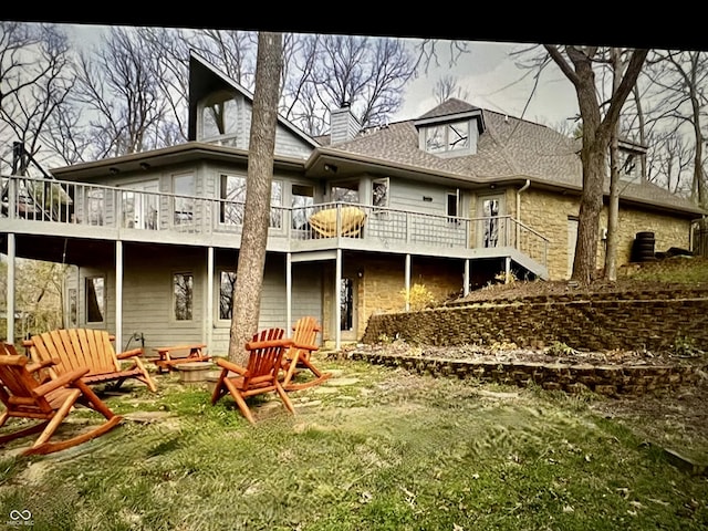 rear view of house featuring a wooden deck, a fire pit, and a lawn