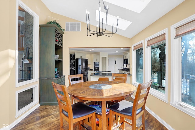 dining area with a wealth of natural light, an inviting chandelier, dark wood-type flooring, and vaulted ceiling with skylight