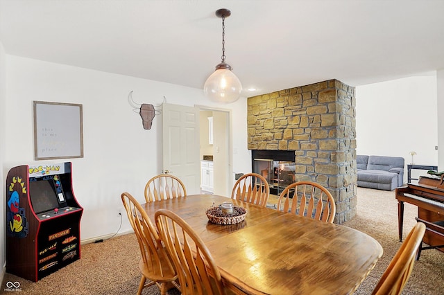 dining space with carpet floors and a stone fireplace