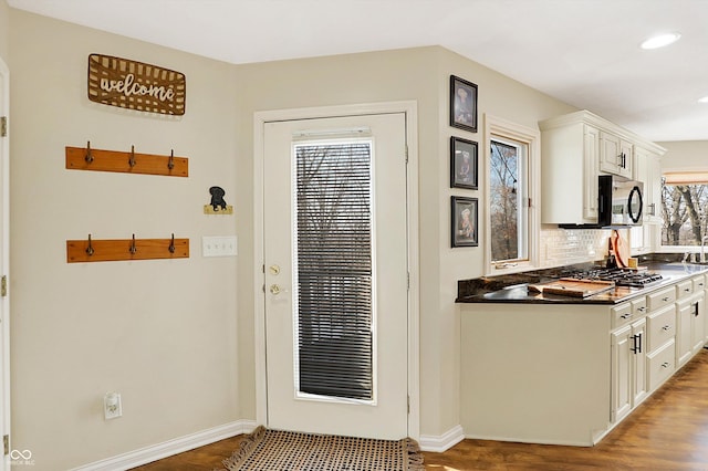 kitchen featuring stainless steel gas stovetop, hardwood / wood-style flooring, white cabinetry, and tasteful backsplash