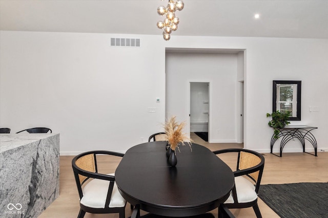 dining space featuring light wood-type flooring and an inviting chandelier