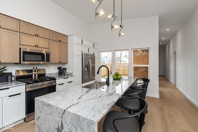 kitchen featuring white cabinets, a center island with sink, sink, and appliances with stainless steel finishes