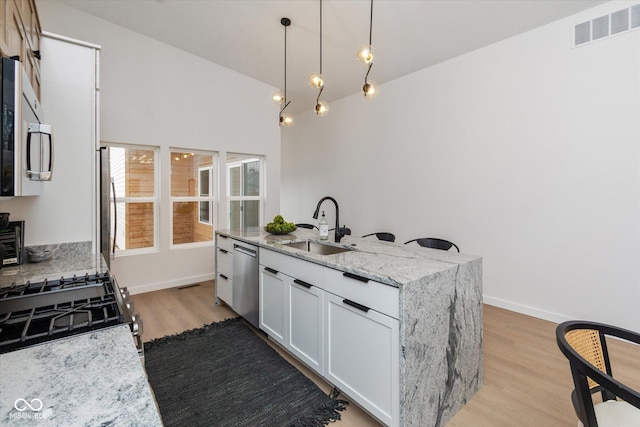 kitchen featuring light stone countertops, sink, hanging light fixtures, stainless steel appliances, and white cabinets