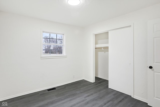 unfurnished bedroom featuring dark hardwood / wood-style flooring and a closet