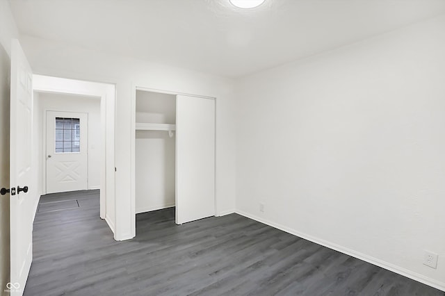 unfurnished bedroom with dark hardwood / wood-style flooring and a closet