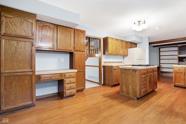 kitchen featuring white refrigerator, light hardwood / wood-style floors, a kitchen island, and built in desk