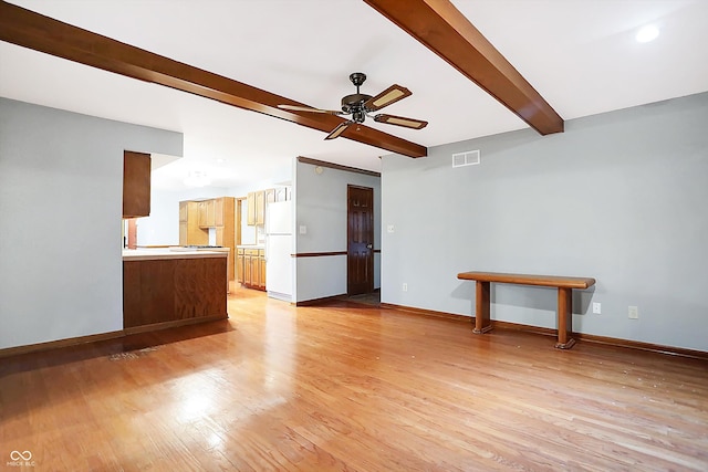 unfurnished living room featuring beamed ceiling, light wood-type flooring, and ceiling fan