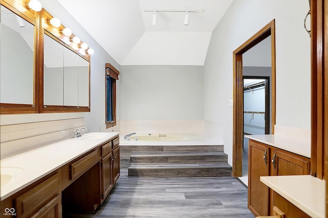 bathroom featuring a washtub, vanity, hardwood / wood-style floors, and lofted ceiling