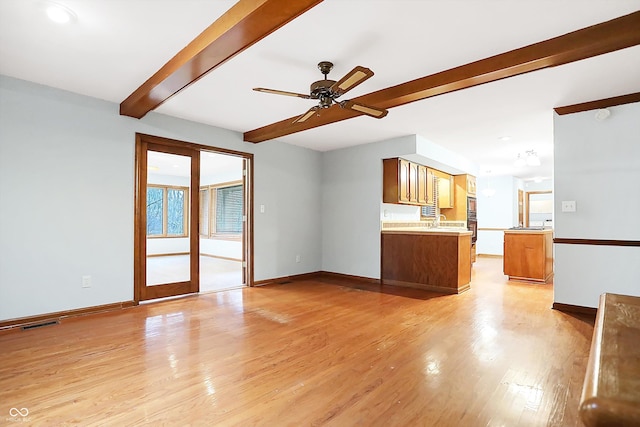 unfurnished living room featuring ceiling fan, beam ceiling, sink, and light hardwood / wood-style flooring