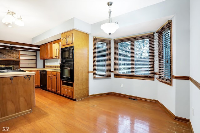 kitchen with light wood-type flooring, hanging light fixtures, and black appliances