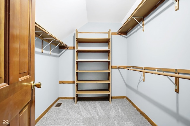 walk in closet featuring light carpet and lofted ceiling