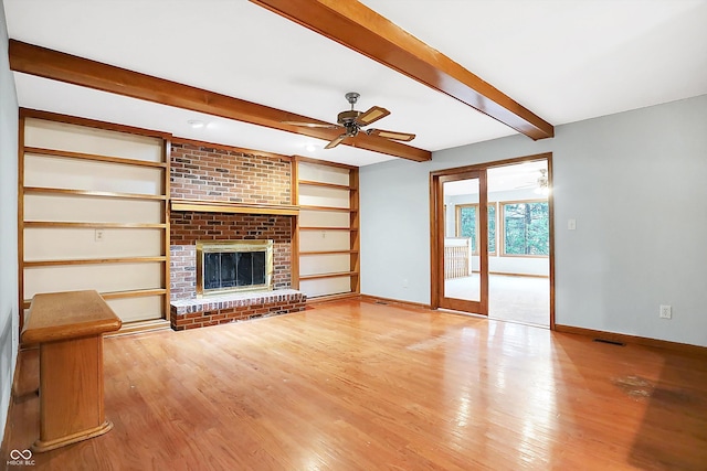 unfurnished living room featuring beam ceiling, ceiling fan, a fireplace, and light wood-type flooring