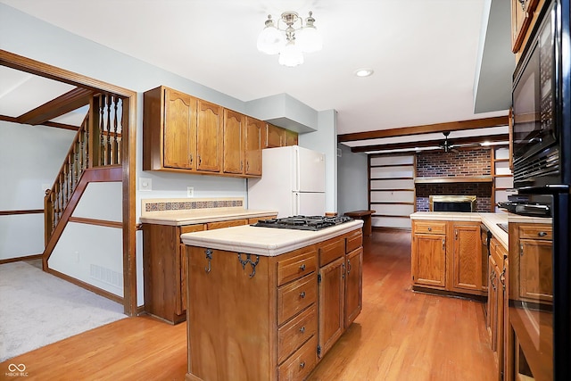 kitchen with black appliances, a center island, light hardwood / wood-style floors, and a fireplace