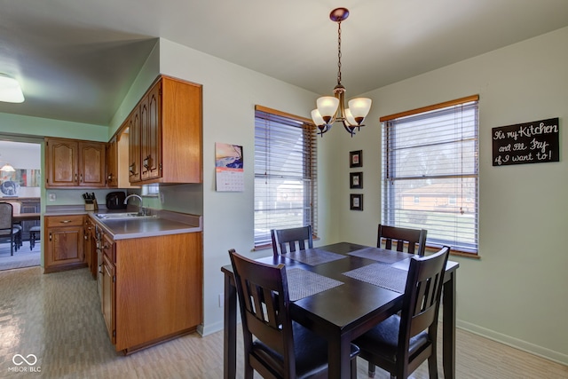 dining area with an inviting chandelier, sink, and light hardwood / wood-style flooring