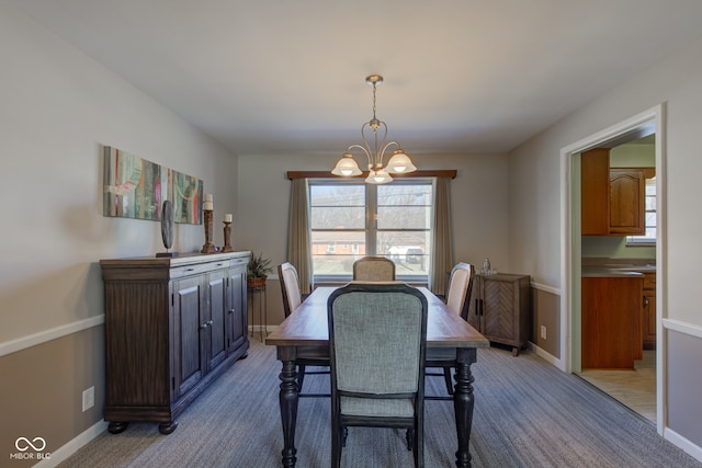 carpeted dining area with a chandelier