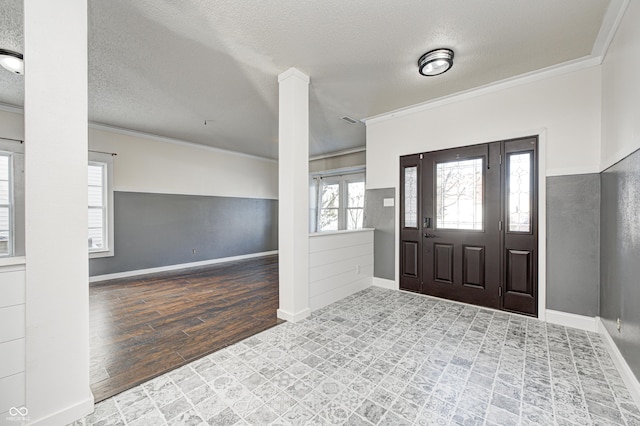 entrance foyer featuring light hardwood / wood-style floors, a textured ceiling, decorative columns, and ornamental molding