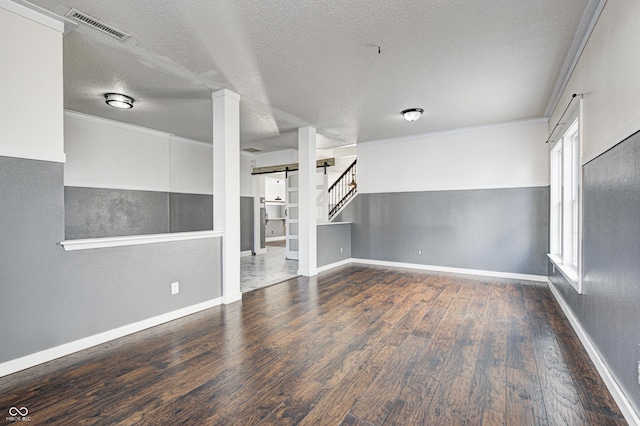 spare room with a textured ceiling, dark hardwood / wood-style flooring, and crown molding