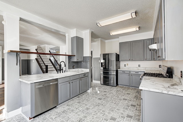 kitchen with appliances with stainless steel finishes, gray cabinetry, a textured ceiling, crown molding, and sink