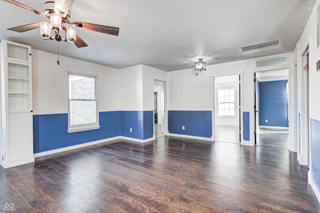 empty room with ceiling fan, dark hardwood / wood-style flooring, and a textured ceiling