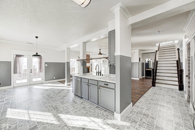 kitchen with gray cabinetry, dishwasher, pendant lighting, light stone counters, and sink