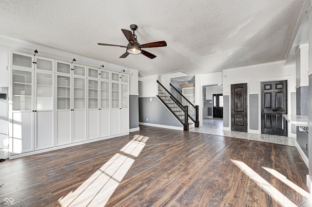 unfurnished living room with ceiling fan, dark hardwood / wood-style flooring, and a textured ceiling