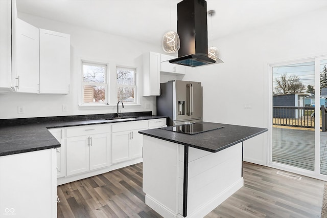 kitchen with sink, high end refrigerator, pendant lighting, island range hood, and white cabinets