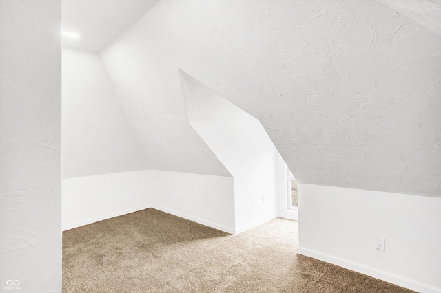 additional living space featuring carpet, lofted ceiling, and a textured ceiling