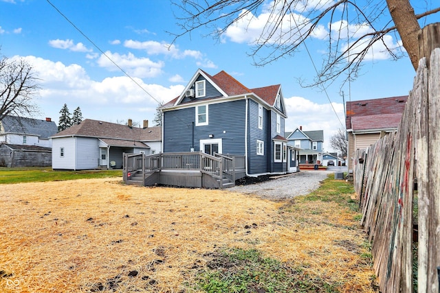 back of property featuring a deck and a lawn