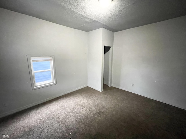 carpeted empty room featuring a textured ceiling