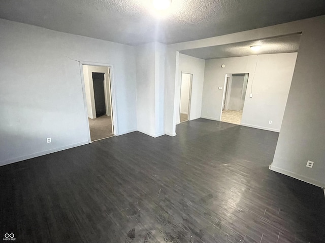 unfurnished room with a textured ceiling and dark hardwood / wood-style flooring