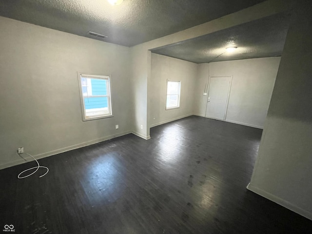 unfurnished room with dark hardwood / wood-style flooring and a textured ceiling