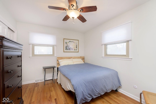 bedroom with multiple windows, light wood-type flooring, a closet, and ceiling fan