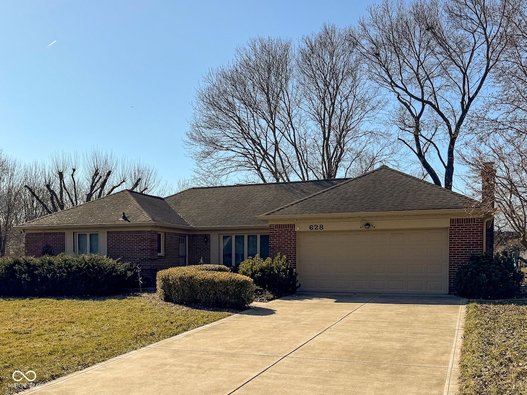 ranch-style house featuring driveway, a chimney, an attached garage, a front lawn, and brick siding