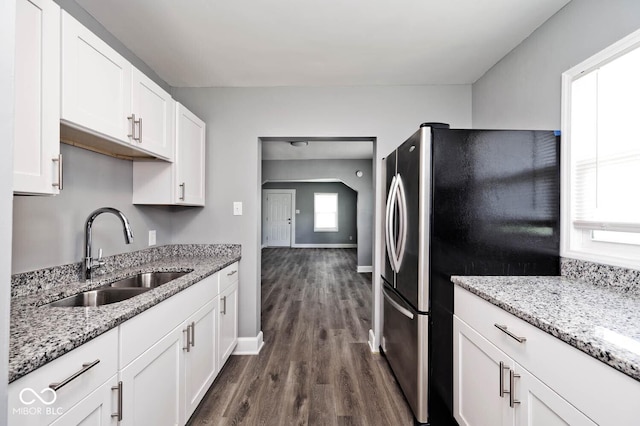 kitchen with stainless steel fridge, dark hardwood / wood-style flooring, light stone counters, sink, and white cabinets