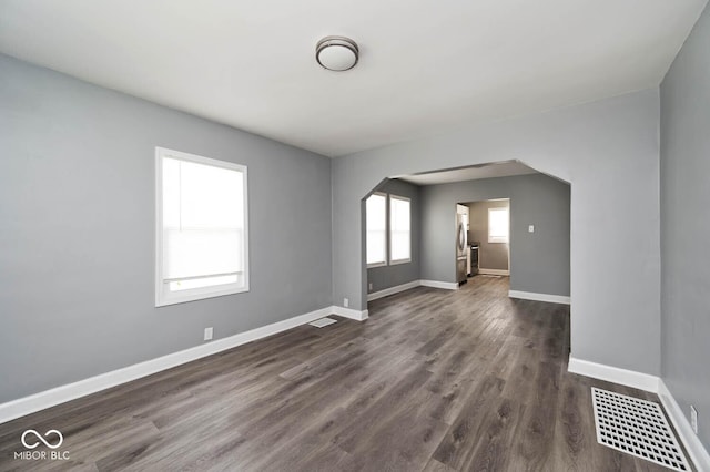 unfurnished room with dark wood-type flooring and a healthy amount of sunlight