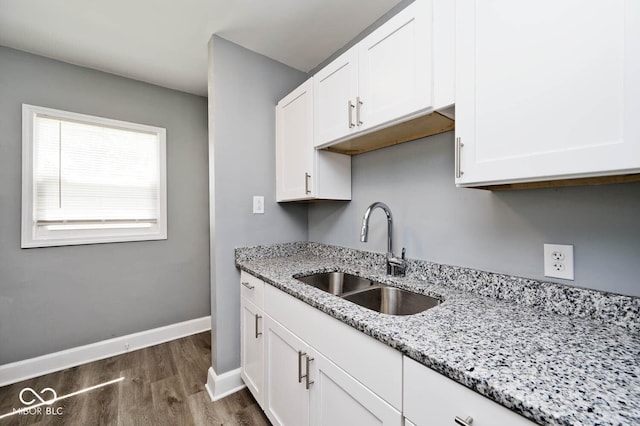 kitchen with dark hardwood / wood-style flooring, light stone counters, white cabinetry, and sink