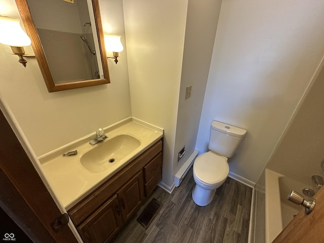 bathroom with vanity, hardwood / wood-style flooring, toilet, and a baseboard heating unit